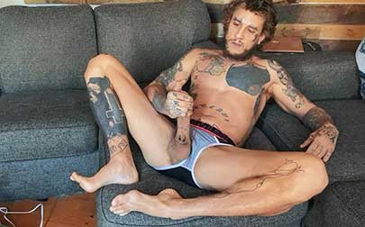 Bo Sinn settles in on the couch in his briefs to thoroughly fuck himself. He strokes his hard dick and pulls it out to jack it hard, then lubes up his hole and slides a few of his fingers inside.